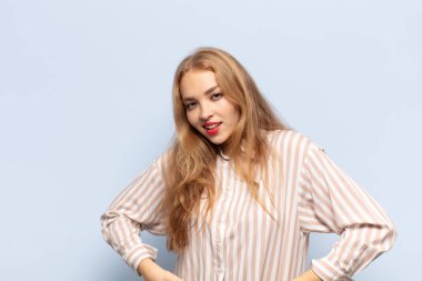 Sarışın kadın neşeli bir şekilde gülümsüyor. Olumlu, mutlu, kendinden emin ve rahat bir ifadeyle.