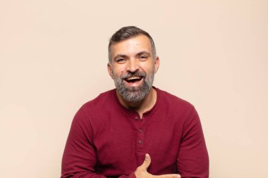 Yetişkin yakışıklı bir adam komik bir şakaya yüksek sesle gülüyor, mutlu ve neşeli hissediyor, eğleniyor.