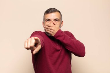 Yetişkin yakışıklı adam sana gülüyor, kamerayı gösteriyor ve seninle dalga geçiyor ya da alay ediyor.