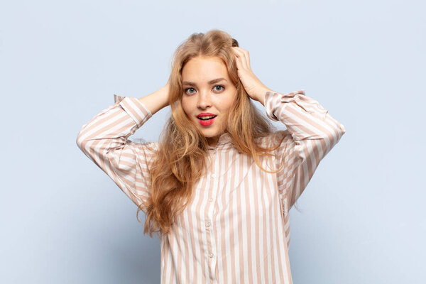 блондинка, поднимающая руки к голове, с открытым ртом, чувствующая себя чрезвычайно удачливой, удивленной, взволнованной и счастливой