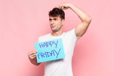 Genç adam şaşkın ve şaşkın hissediyor, başını kaşıyor ve yana bakıyor.