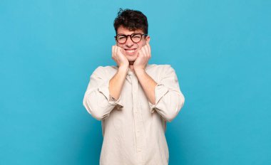 Genç adam sinirli, stresli ve sinirli görünüyor, iki kulağını da sağır edici bir ses, ses ya da yüksek sesle kapatıyor.