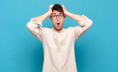 Genç adam heyecanlı ve şaşırmış görünüyor, ağzı açık, elleri başının üstünde, şanslı bir kazanan gibi hissediyor.