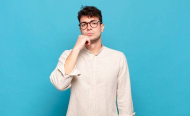 Genç adam ciddi görünüyor, kafası karışık, kararsız ve düşünceli, seçenekler ve seçimler arasında şüpheci.