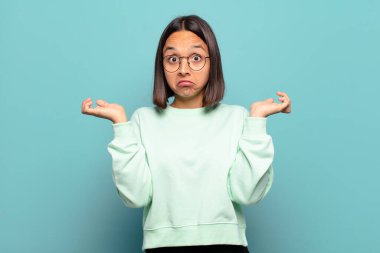 Genç İspanyol kadın şaşkın ve kafası karışık, şüpheci, farklı seçenekleri tartıyor veya komik bir ifadeyle seçiyor.