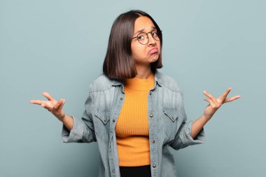 young hispanic woman feeling clueless and confused, having no idea, absolutely puzzled with a dumb or foolish look