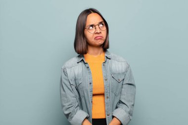 Genç İspanyol kadın şaşkın ve şaşkın görünüyor, merak ediyor veya bir sorunu çözmeye çalışıyor veya düşünüyor.