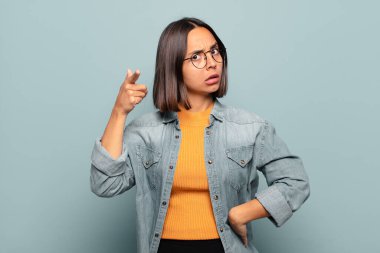 Öfkeli, çılgın bir patrona benzeyen sinirli bir ifadeyle kameraya bakan genç İspanyol kadın.