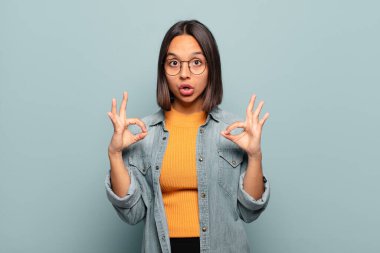 Genç İspanyol kadın şok olmuş, şaşırmış ve şaşırmış hissediyor. Onaylıyor. İki eliyle işaret veriyor.