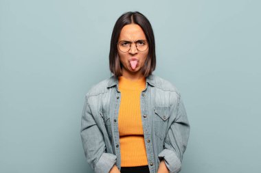 Genç İspanyol kadın tiksinti ve tedirginlik duyuyor, dilini dışarı çıkarıyor, iğrenç ve iğrenç bir şeyden hoşlanmıyor.