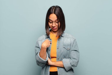 Genç İspanyol kadın neşeyle gülümsüyor, yere bakıyor ve göğsüne işaret ediyor.