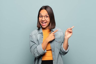 Genç İspanyol kadın sevinçli ve şaşırmış hissediyor. Şok olmuş bir ifadeyle gülümsüyor ve bir tarafı işaret ediyor.