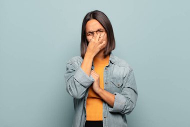 Genç İspanyol kadın iğreniyor, kötü ve nahoş bir koku duymamak için burnunu tutuyor.