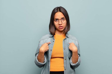 Genç İspanyol kadın şaşkın, şaşkın ve güvensiz hissediyor, kendini gösterip kim olduğunu soruyor, ben mi??