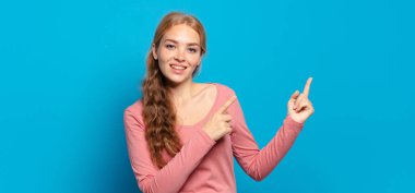 Sarışın, güzel bir kadın mutlu bir şekilde gülümsüyor ve her iki elinde fotokopi uzayında nesne gösteriyor.