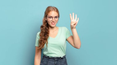 Sarışın, güzel bir kadın gülümsüyor ve arkadaş canlısı görünüyor, dört ya da dört numarayı gösteriyor, eli önde, geri sayıyor.