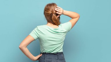 Sarışın, güzel, düşünceli, şüpheci, kaşınan, kafası karışık, kafası karışmış, arkadan ya da arkadan bakan kadın.