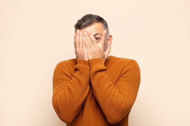 Yetişkin, yakışıklı bir adam korkmuş ya da utanmış hissediyor. Gözleri yarı kapalı ya da elleri kapalı gözetliyor.