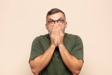 Yetişkin, yakışıklı bir adam endişeli, üzgün ve korkmuş, elleriyle ağzını kapatmış, endişeli ve berbat görünüyor.