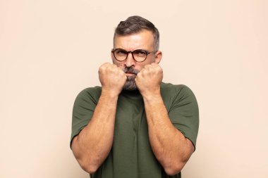 Kendine güvenen, sinirli, güçlü ve agresif, yumrukları boks pozisyonunda dövüşmeye hazır yakışıklı bir adam.