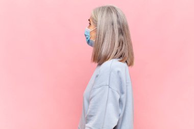 Profil görünümlü orta yaşlı kadın ileriyi kopyalamak istiyor, düşünüyor, hayal ediyor ya da hayal kuruyor.