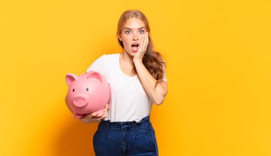 Şok olmuş ve korkmuş hissediyorum, ağzı açık ve elleri yanaklarında korkmuş görünüyor.