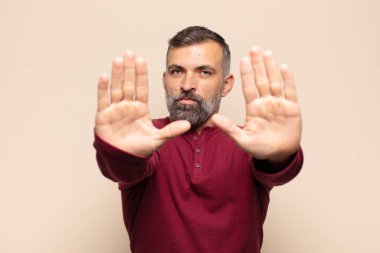 Yetişkin, yakışıklı bir adam ciddi, mutsuz, kızgın ve hoşnutsuz görünüyor. Ya da her iki avuçta da dur diyor.