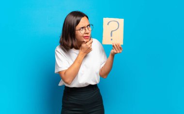 Soru işareti konsepti olan genç ve güzel bir kadın.