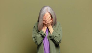 Son sınıf öğrencisi üzgün, sinirli ve depresif hissediyor. İki eliyle yüzünü kapatıyor, ağlıyor.