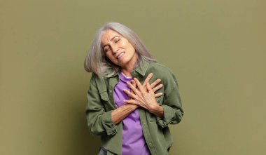 Son sınıf öğrencisi üzgün, yaralı ve kalbi kırık görünüyor, iki elini de kalbine yakın tutuyor, ağlıyor ve depresif hissediyor.