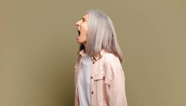 Yaşlı kadın öfkeyle bağırıyor, agresif bağırıyor, stresli ve sinirli görünüyor.