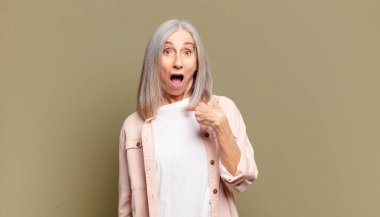 Şok olmuş ve ağzı açık, kendini işaret eden son sınıf öğrencisi bir kadın.