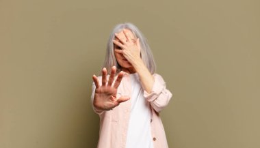 Son sınıf öğrencisi kadın yüzünü eliyle kapatıyor ve kamerayı durdurmak için diğer elini öne koyuyor. Fotoğraf ya da resimleri reddediyor.