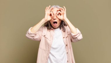 Son sınıf öğrencisi kadın şaşkın, şaşkın ve şaşırmış, elinde şaşkın, inançsız bir bakışla gözlük tutuyor.