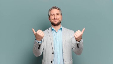 Yetişkin iş adamı mutlu bir şekilde gülümsüyor, mutlu görünüyor, tasasız ve pozitif hissediyor.