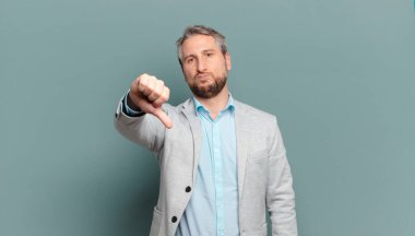 Yetişkin iş adamı kızgın, sinirli, hayal kırıklığına uğramış ya da hoşnutsuz, ciddi bir bakışla başparmaklarını göstermiyor.