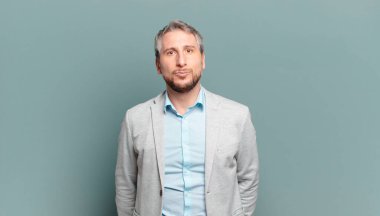 Yetişkin iş adamı dudaklarını tatlı, eğlenceli, mutlu, sevimli bir ifadeyle birbirine bastırıyor ve öpüşüyor.