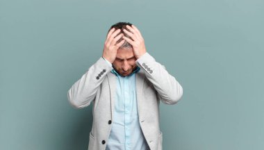 Yetişkin iş adamı stresli ve hayal kırıklığına uğramış hissediyor, ellerinizi havaya kaldırıyor, yorgun, mutsuz ve migren ağrısı çekiyor.