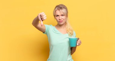 Sarışın kadın kızgın, sinirli, hayal kırıklığına uğramış ya da hoşnutsuz, ciddi bir bakışla başparmaklarını göstermiyor.