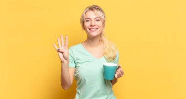 Sarışın kadın gülümsüyor ve arkadaş canlısı görünüyor, 4 ya da 4 numarayı gösteriyor, eli önde, geriye doğru sayıyor.