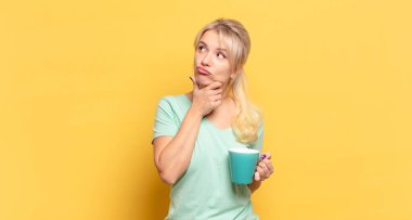 Sarışın kadın düşünüyor, kuşkulu ve şaşkın hissediyor, farklı seçenekleri var, hangi kararı vereceğini merak ediyor.