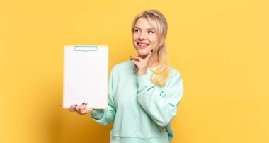 Sarışın kadın mutlu bir şekilde gülümsüyor ve hayal kuruyor ya da şüphe ediyor.