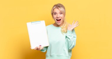 Sarışın kadın mutlu, heyecanlı, şaşırmış ya da şaşırmış hissediyor. İnanılmaz bir şeye gülümsüyor ve şaşırıyor.