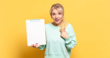 Sarışın kadın mutlu, şaşkın ve gururlu, heyecanlı, şaşkın bakışlarla kendini işaret ediyor.