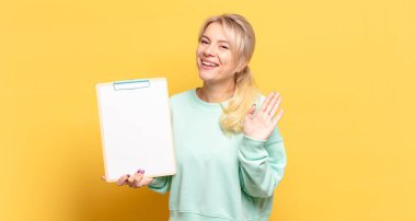 Sarışın kadın mutlu ve neşeyle gülümsüyor, el sallıyor, seni selamlıyor ya da hoşça kal diyor.