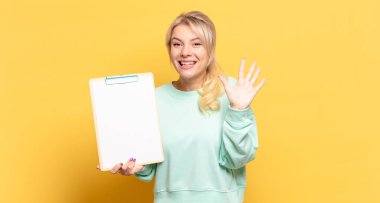 Sarışın kadın gülümsüyor ve arkadaş canlısı görünüyor, 5 ya da 5 numarayı gösteriyor, eli önde, geriye doğru sayıyor.