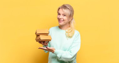 Sarışın kadın mutlu bir şekilde gülümsüyor, mutlu hissediyor ve fotokopi alanında avucunun içinde bir konsept gösteriyor.