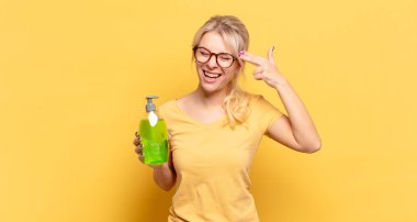 Sarışın kadın mutsuz ve stresli görünüyor, intihar jesti elle silah işareti yapıyor, kafasını işaret ediyor.