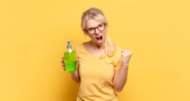 Sarışın kadın öfkeli bir ifadeyle ya da yumruklarıyla başarıyı kutlarken agresif bir şekilde bağırıyor.