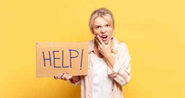 Sarışın, ağzı ve gözleri açık ve eli çenesinde olan bir kadın. Hoş olmayan bir şok geçiriyor. Ne diyor?